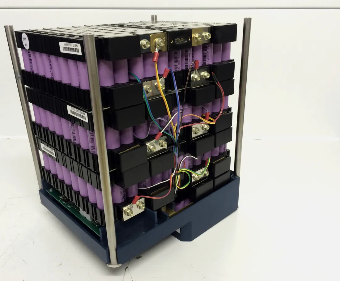 Assembled battery module on a steel frame, showing cell holders, busbars and balance wiring.